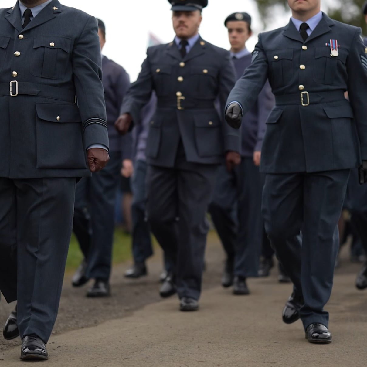 a group of men in uniform walking on a road